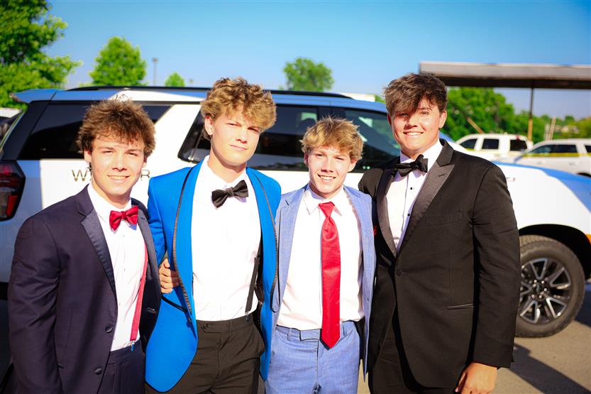 Four young men stand together and smile